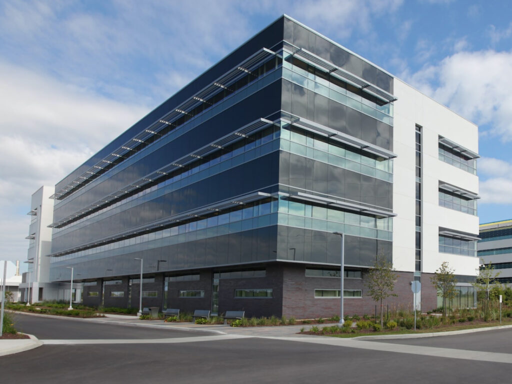 A large glass building with a brick bottom and white and black trim