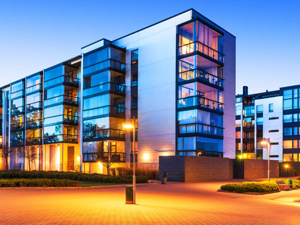 The outside of a white apartment building that has glass balconies with black trim