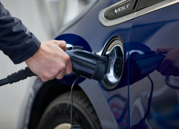 An EvoCharge charger in the forefront with a man charging his car in the background