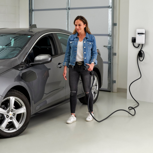 A woman charging her electric vehicle in the garage.